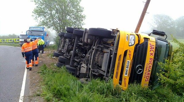 Recovery crew at an overturned lorry on a roadside verge